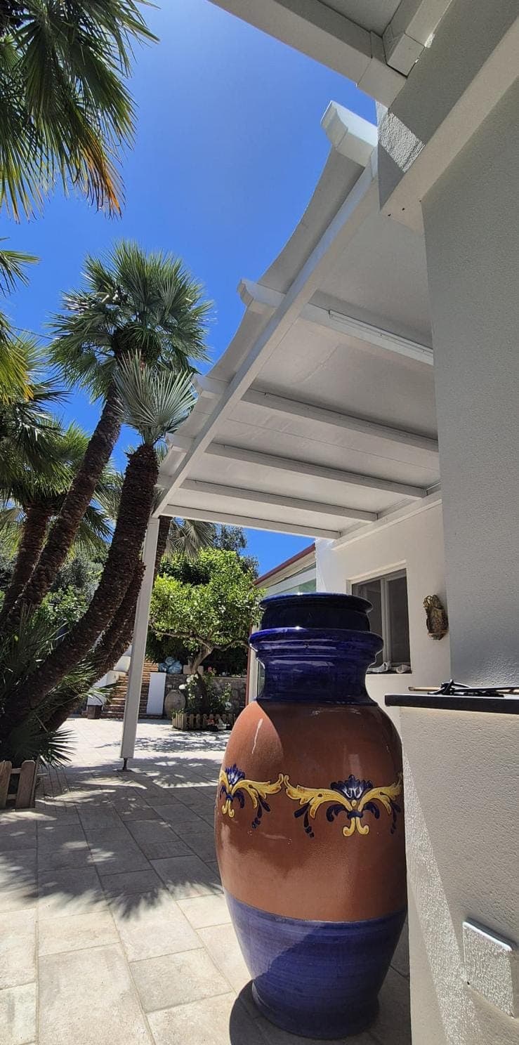 Pergola bianca a lamelle su una terrazza privata ad Anacapri, accanto a un grande vaso di ceramica