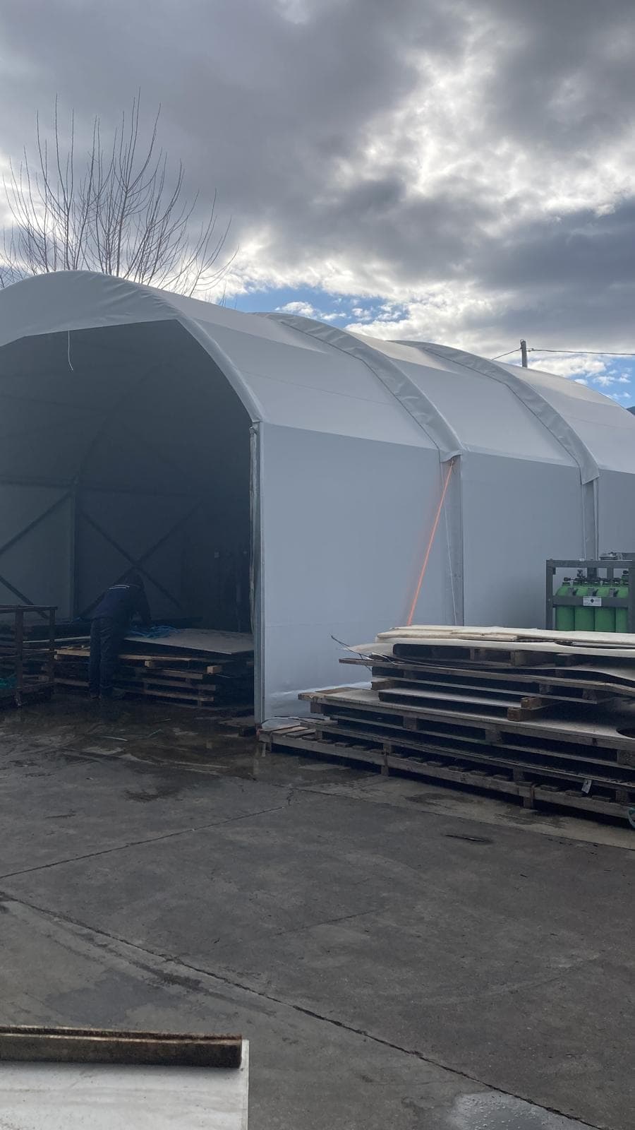 Tunnel in PVC bianco con struttura ad arco, aperto sul piazzale di un'azienda