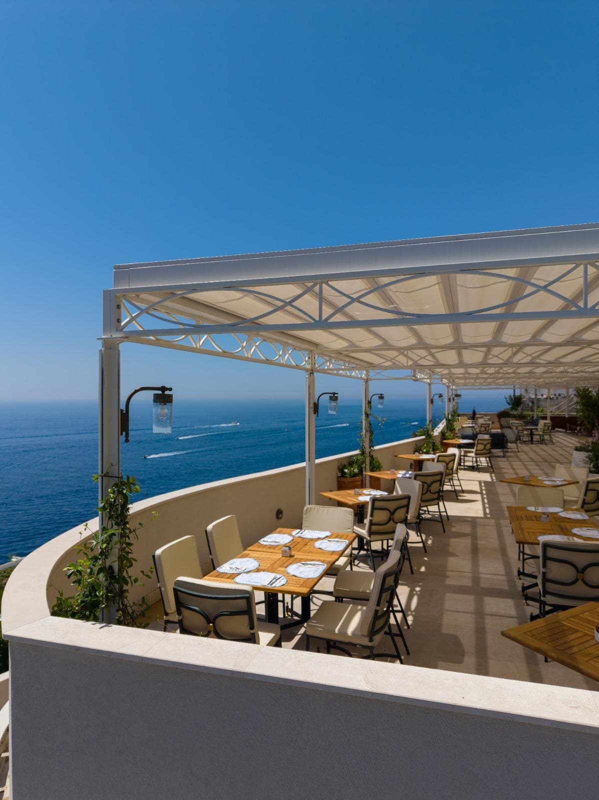 Tavoli sotto la pergola della terrazza, con la copertura tesa e il golfo alle spalle